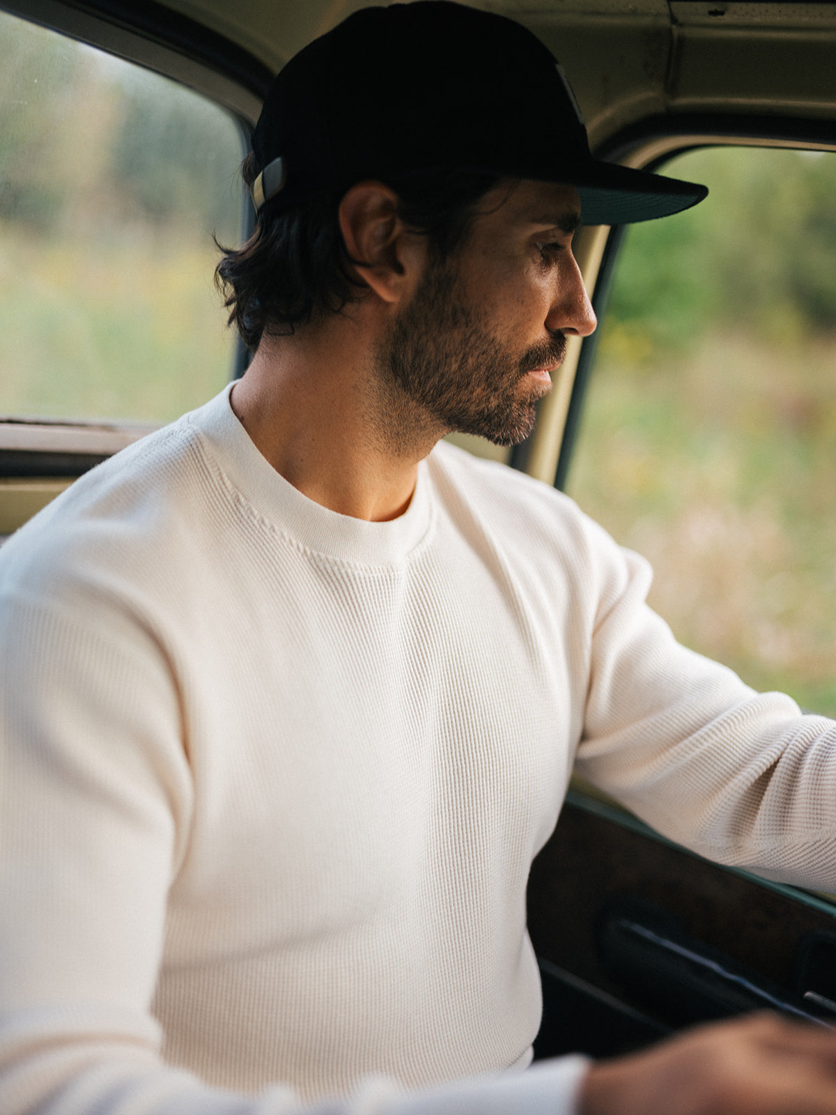 Natural waffle thermal and black cap behind the wheel of a pickup, Fall 2026 lifestyle