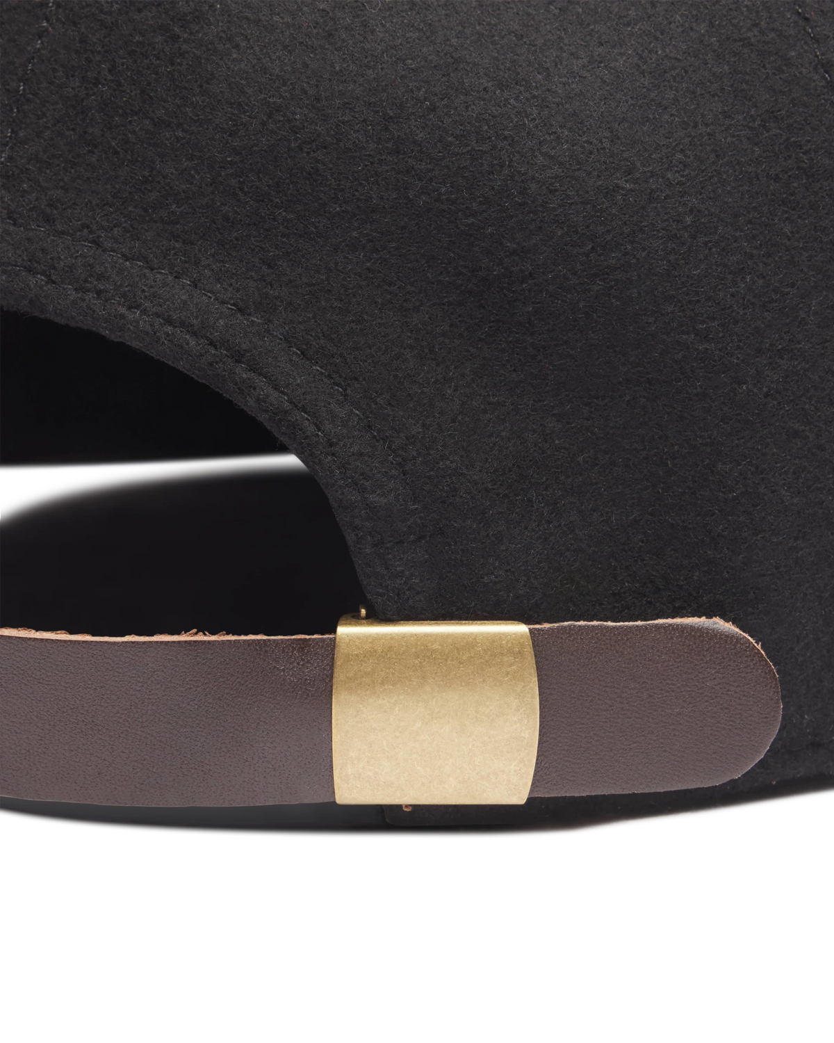 Close-up of brown leather strapback and antique brass clasp on the Black wool hat
